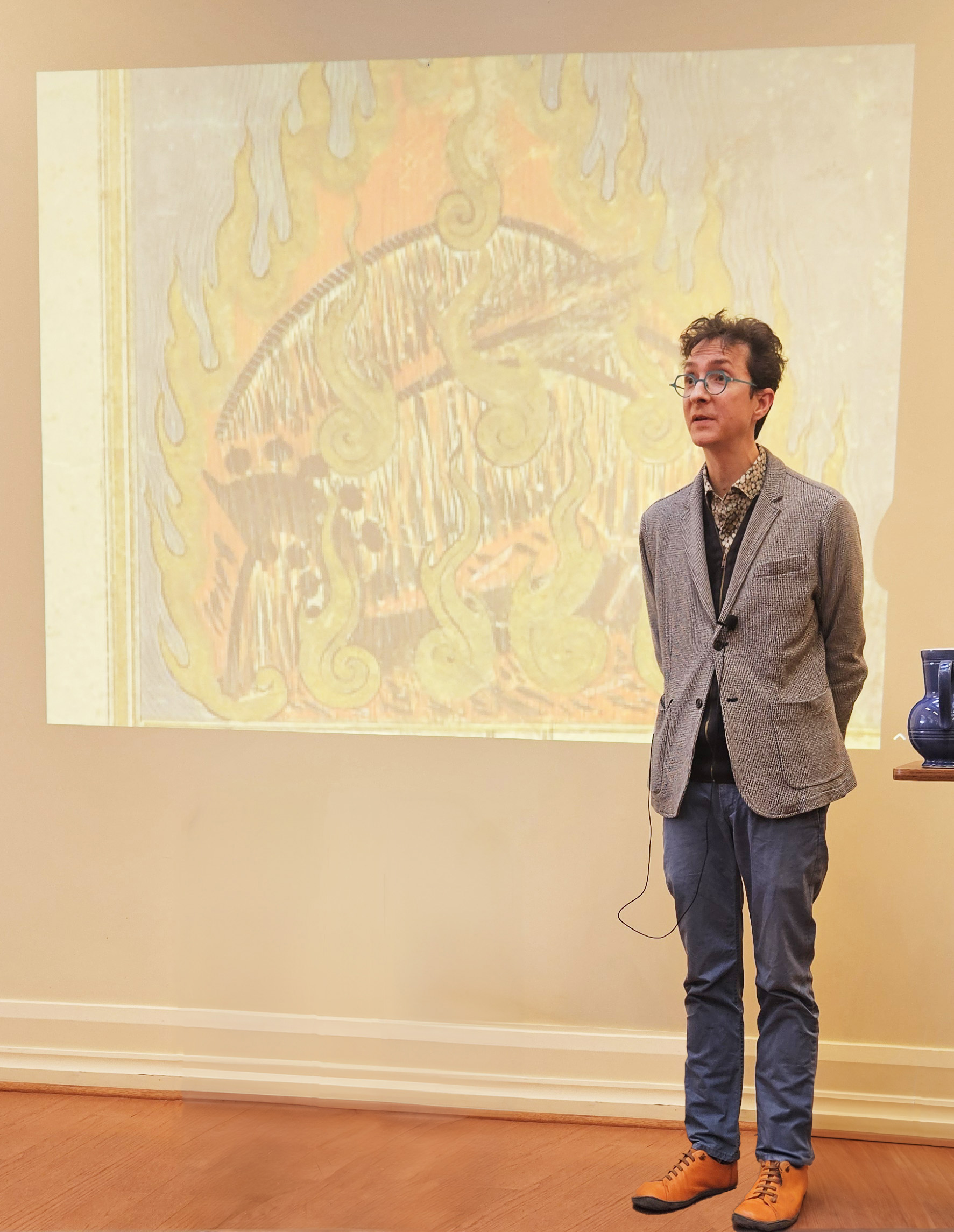 Andrew Hicks in front of a projection of a classical Persian image